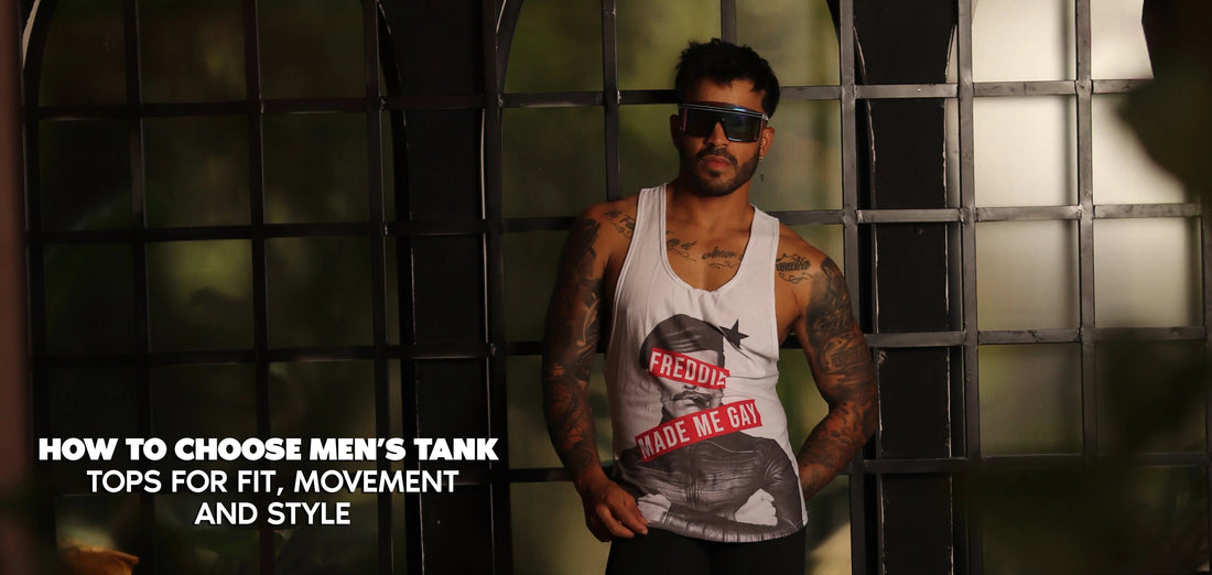 Tattooed model wearing sunglasses and a white graphic tank top in front of an industrial window.